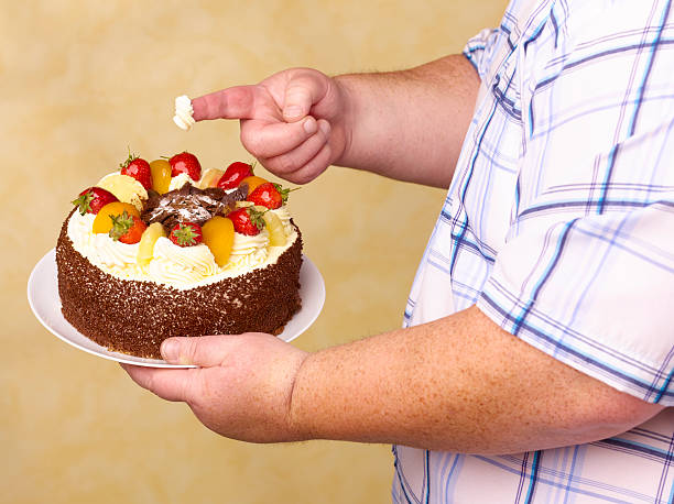 obese man holding fruit gâteaux with cream on - junk food stock pictures, royalty-free photos & images