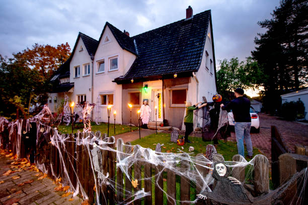 October 2020, Lower Saxony, Hanover: Marleen Salewski and Julian Witte decorate a cross with artificial cobwebs in their front garden in the Bothfeld...