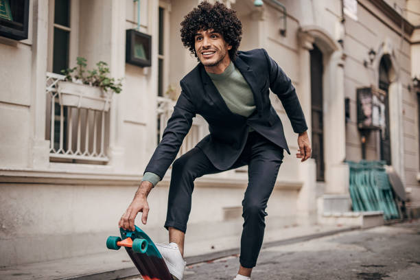one cheeful businessman skateboarding to his workplace - fashion stock pictures, royalty-free photos & images