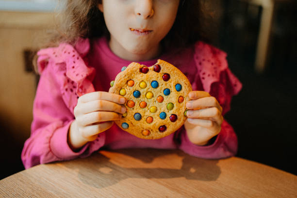 one little girl eating candy cookie - junk food stock pictures, royalty-free photos & images