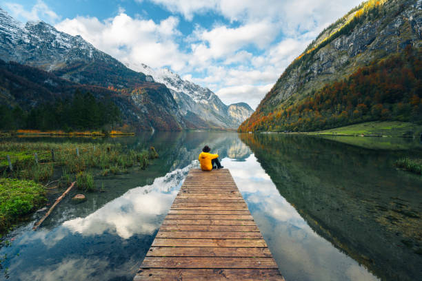 one man sitting on a boat pier admiring the konigssee lake, bavaria, germany - travel stock pictures, royalty-free photos & images