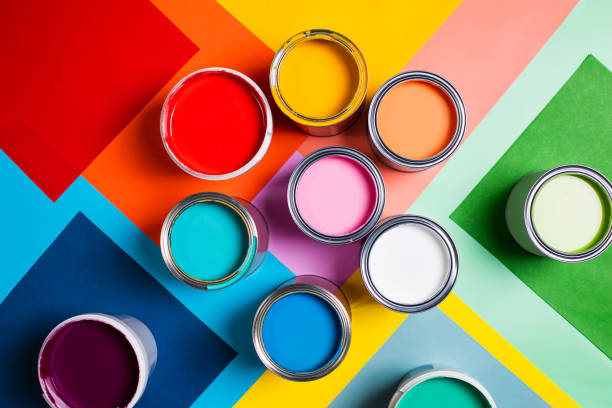 open cans with bright multicolored paints arranged on colorful geometric background divided in several parts representing concept of home repair and renovation supplies. performed in flat lay style. concept of redecoration in