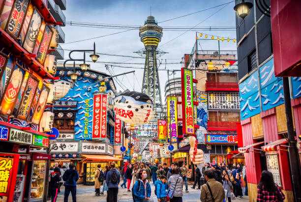 osaka tower und blick auf die neon-werbung in shinsekai bezirk in der dämmerung, osaka, japan - travel stock-fotos und bilder