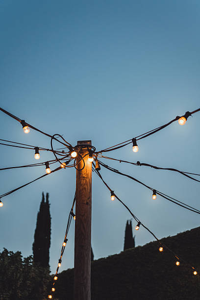 outdoor string lights illuminating wooden pole against twilight sky. - garden decoration stock pictures, royalty-free photos & images