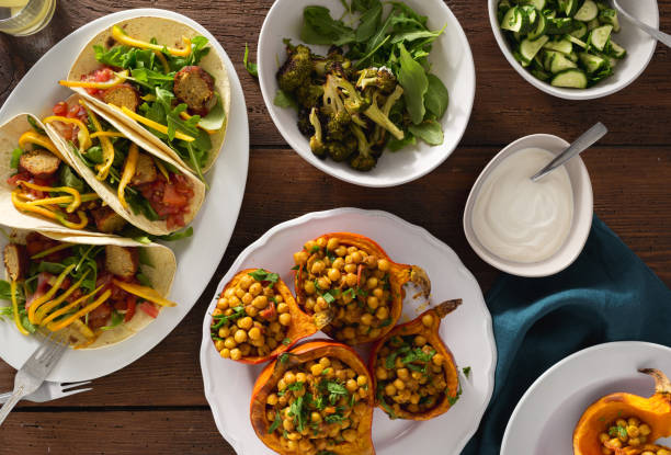 overhead view autumn dinner table with baked pumpkin with chickpeas curry, tortilla with falafel and salad - food stock pictures, royalty-free photos & images