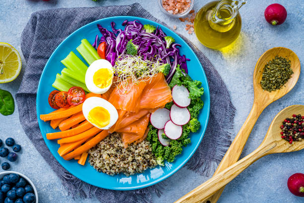 overhead view of a fresh salmon, quinoa, boiled eggs and vegetables salad plate. healthy eating and dieting concept - food stock pictures, royalty-free photos & images