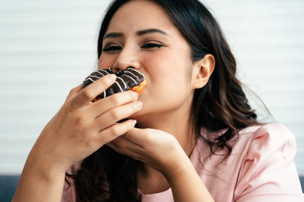 overweight happy woman with a donut - junk food stock pictures, royalty-free photos & images