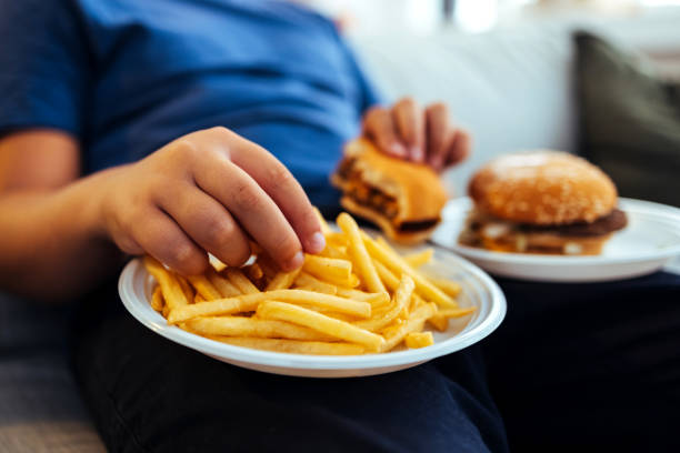 overweight teenage boy eating too much fried food - junk food stock pictures, royalty-free photos & images