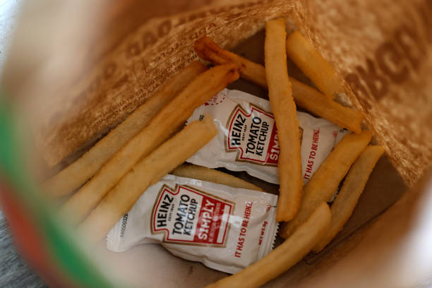 Packets of Heinz ketchup sit in the bottom of a Burger King bag with french fries on April 12, 2021 in San Anselmo, California. Packets of ketchup...