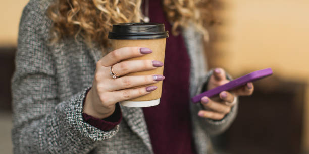 paper cup and mobile phone in hand - junk food stock pictures, royalty-free photos & images