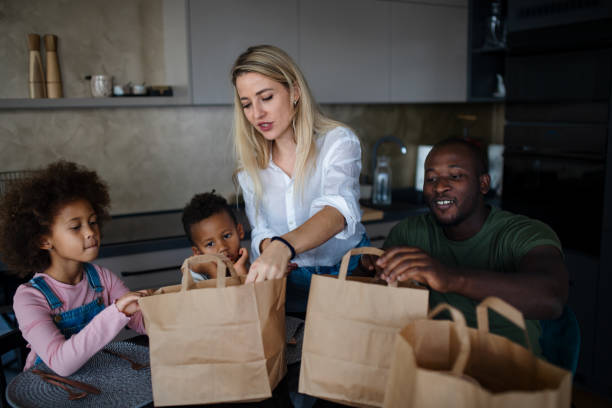 parents bringing take away food and serving at table to little children at home. - junk food stock pictures, royalty-free photos & images