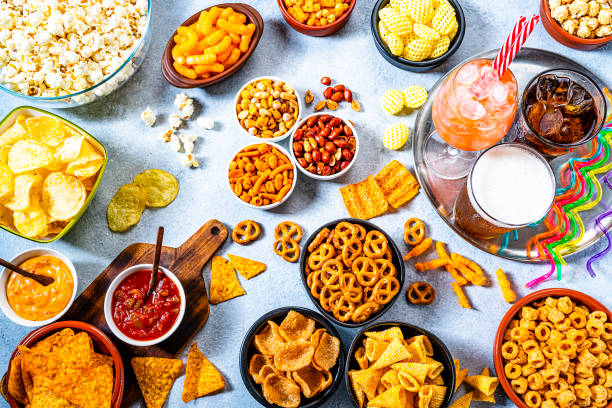 party table with salty snacks and drinks shot from above - junk food stock pictures, royalty-free photos & images