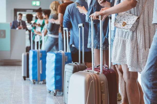 passengers with luggage waiting in line at airport - travel stock pictures, royalty-free photos & images