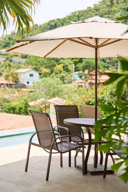 patio table and chairs with an umbrella sitting by a pool in summer - garden decoration stock pictures, royalty-free photos & images