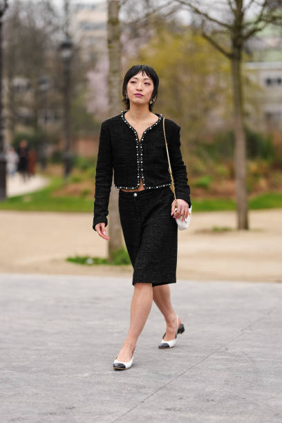 Patricia Zhou wears silver Chanel earrings, black tweed pearl detail cropped Chanel blazer jacket, black mid-rise tweed bermuda Chanel shorts, white...