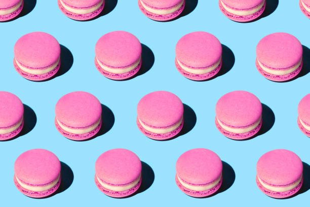 pattern made of tasty pink purple color macaroons on pastel blue background. - food stock pictures, royalty-free photos & images
