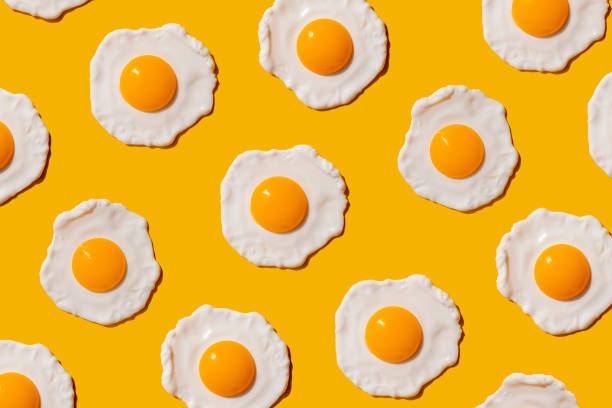pattern of fried eggs against yellow background - food stock pictures, royalty-free photos & images