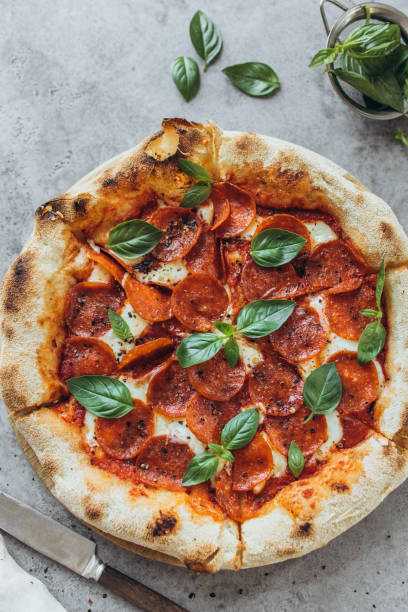 pepperoni pizza garnished with basil leaves - junk food stock pictures, royalty-free photos & images