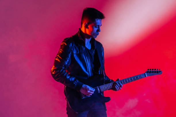 performance of a rock guitarist playing a musical song on a guitar in neon light - concert stock pictures, royalty-free photos & images