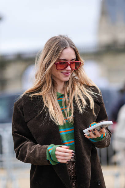 Pernille Teisbaek wears a green and pink striped top, a brown oversized jacket, sunglasses, outside Loewe, during the Womenswear Fall/Winter...