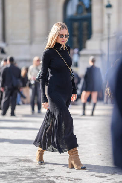 Pernille Teisbaek wears black sunglasses, black turtleneck long sleeve flowy midi dress, shiny black quilted Chanel leather bag, light brown black...
