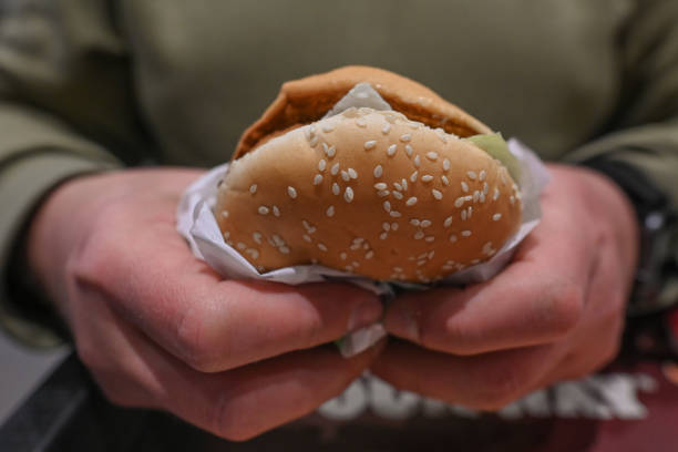 Person enjoys a burger inside a fast food restaurant, on March 28 in Krakow, Poland.