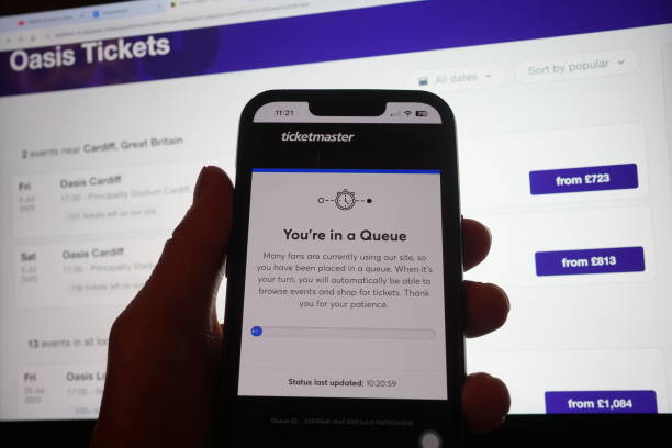 Person in a queue to access the Ticketmaster website on their phone, with the StubHub website in the background, detailing information about Oasis...