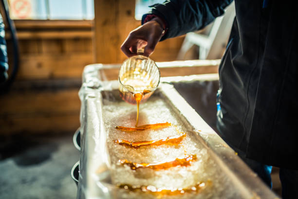 person pouring maple syrup onto snow at sugar shack - food stock pictures, royalty-free photos & images