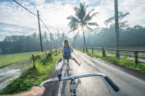 personal perspective- couple cycling near rice fields at sunrise, indonesia - travel stock pictures, royalty-free photos & images