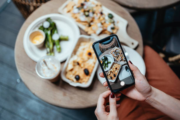 personal perspective of young woman enjoying her home delivery takeaway meal in the balcony, taking photos of delicious food with smartphone before eating it. eating in lifestyle. camera eats first culture. technology in ever