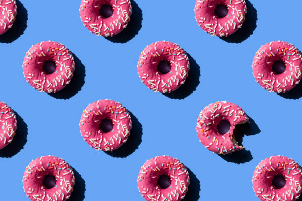 pink doughnut on pastel blue background. chewed donut. - food stock pictures, royalty-free photos & images