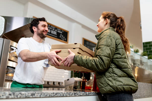 pizzaiolo at work - chef is shovelling fresh prosciutto pizza in the carton pizza box - junk food stock pictures, royalty-free photos & images