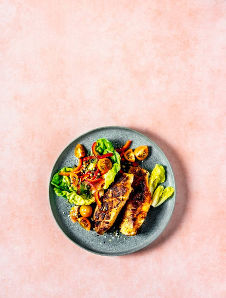 plate of grilled chicken with fresh salad on peach background - food stock pictures, royalty-free photos & images