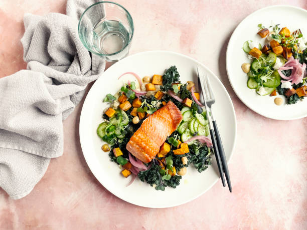 plate of roasted salmon with fresh salad on pink background - food stock pictures, royalty-free photos & images