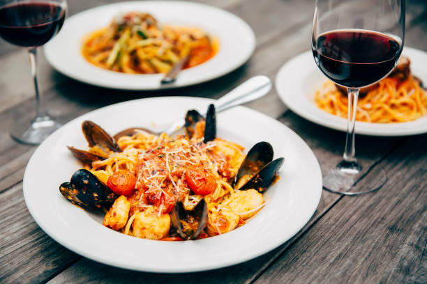 plates of seafood and pasta with wine glasses - food stock pictures, royalty-free photos & images