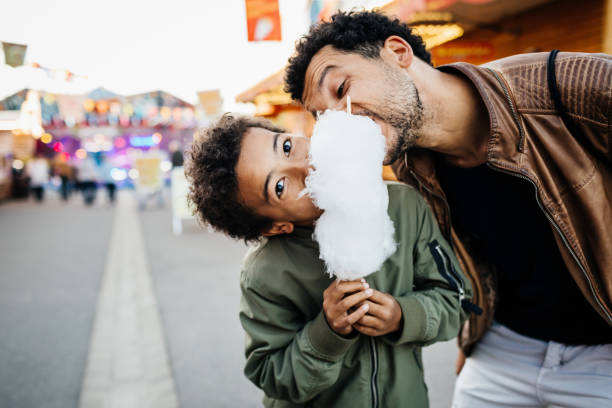 playful father and son sharing candy floss - food stock pictures, royalty-free photos & images