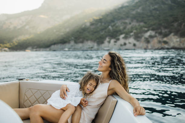 pleasant young family relaxing on a micro motorboat. - travel stock pictures, royalty-free photos & images