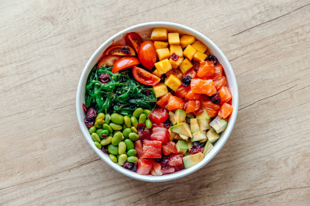 poke bowl with salmon, tuna and variety of fresh vegetables and fruits - junk food stock pictures, royalty-free photos & images