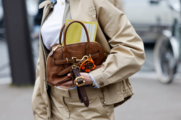 Polina Erofeeva wears white t-shirt, beige Miu Miu jacket with blue checked details, matching mini skirt, brown Miu Miu bag, outside Miu Miu, during...