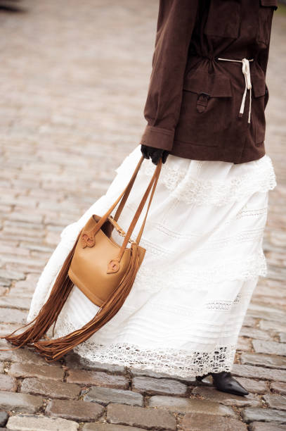 Pornwika Spiecker wears long white skirt, brown jacket and brown bag outside the Munthe fashion show during the Copenhagen Fashion Week Autumn/Winter...