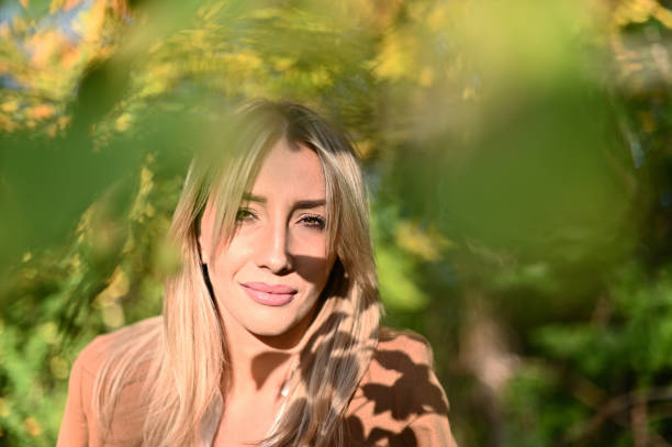 portrait of a beautiful smiling woman standing amongst trees in a park, bosnia and herzegovina - garden decoration stock pictures, royalty-free photos & images