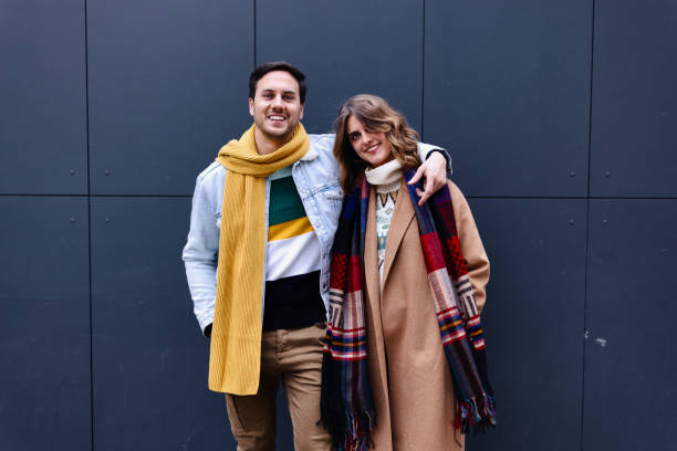 portrait of a young couple standing against dark grey background - fashion stock pictures, royalty-free photos & images