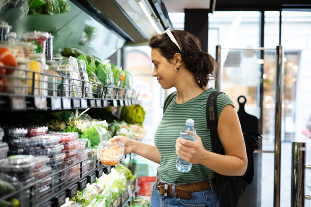 portrait of a young woman buying fresh vegetables at the grocery store - food stock pictures, royalty-free photos & images