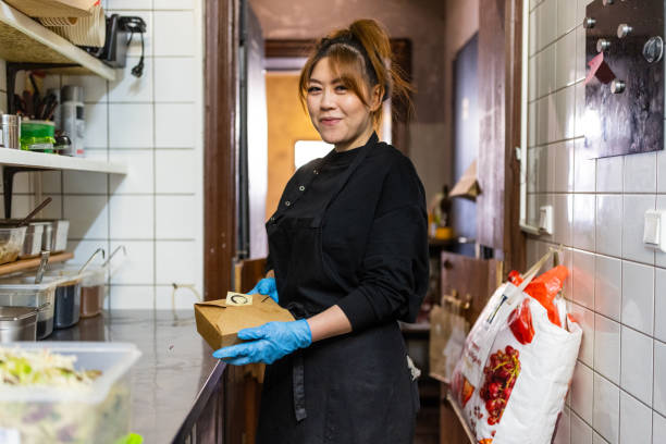 portrait of an asian female preparing food parcel in kitchen - junk food stock pictures, royalty-free photos & images