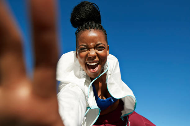 portrait of cheerful young sportswoman with hair bun against clear blue sky - hairstyle stock pictures, royalty-free photos & images