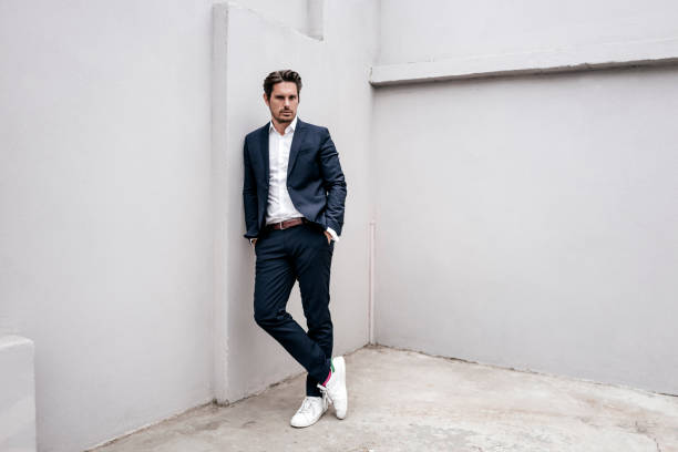 portrait of confident businessman leaning against a wall - fashion stock pictures, royalty-free photos & images