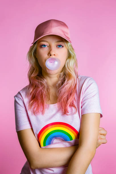 portrait of cool young woman with bubble gum in front of pink background - fashion stock pictures, royalty-free photos & images
