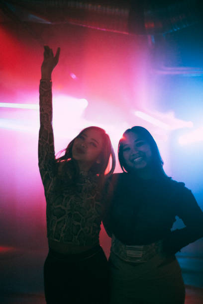 portrait of happy young female friends standing with arms around at nightclub - concert stock pictures, royalty-free photos & images
