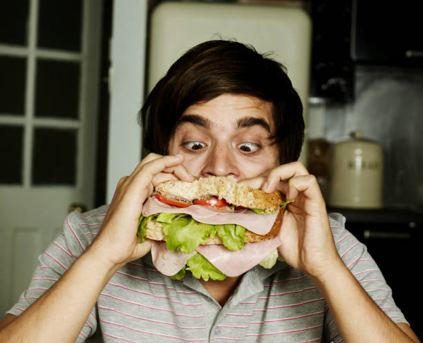 portrait of man eating sandwich - food stock-fotos und bilder