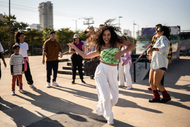 portrait of mid adult woman dancing reggaeton during street party with her friends outdoors - concert stock pictures, royalty-free photos & images